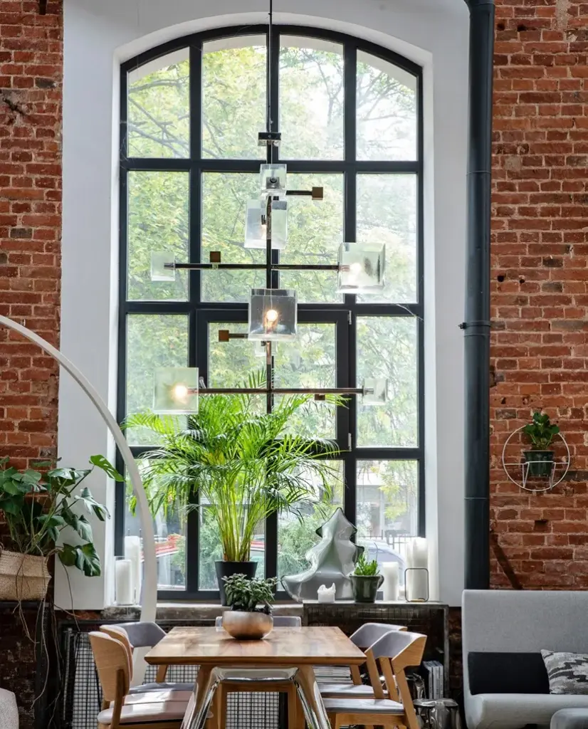 Hohes Stahl-Bogenfenster mit Sprossen in einem Loft mit Ziegelwand