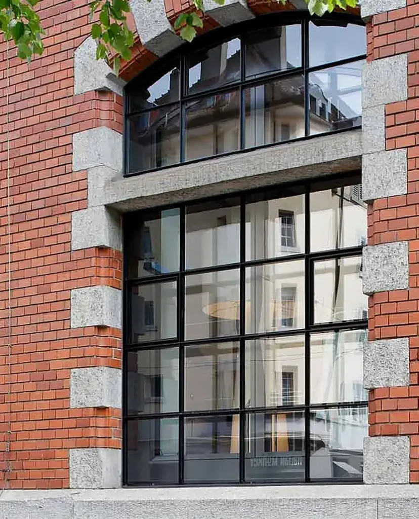 Stahl-Sprossenfenster mit Rundbogen in einer Backsteinfassade